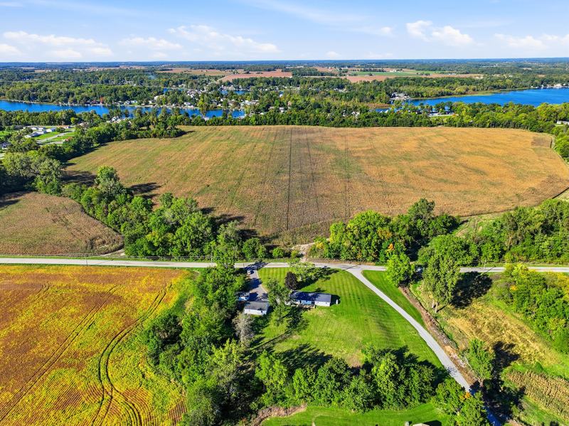 High drone view of farmland, tree lines and lakes stretching to the horizon