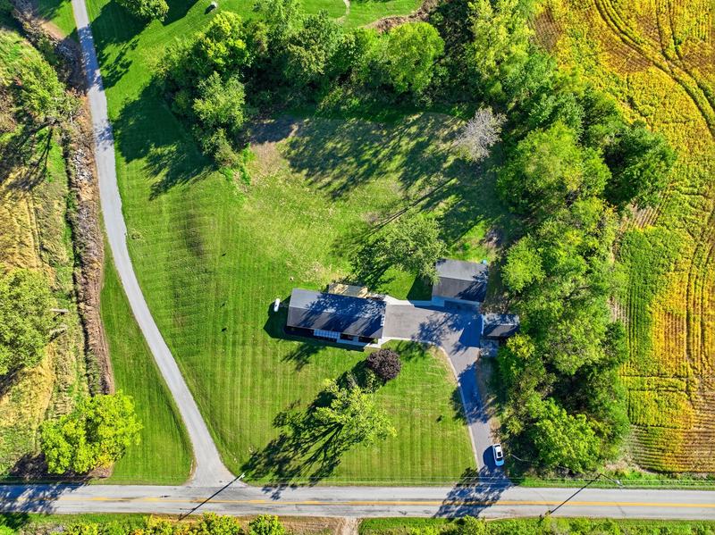 Top-down drone view of a home on a large wooded lot with a winding drive