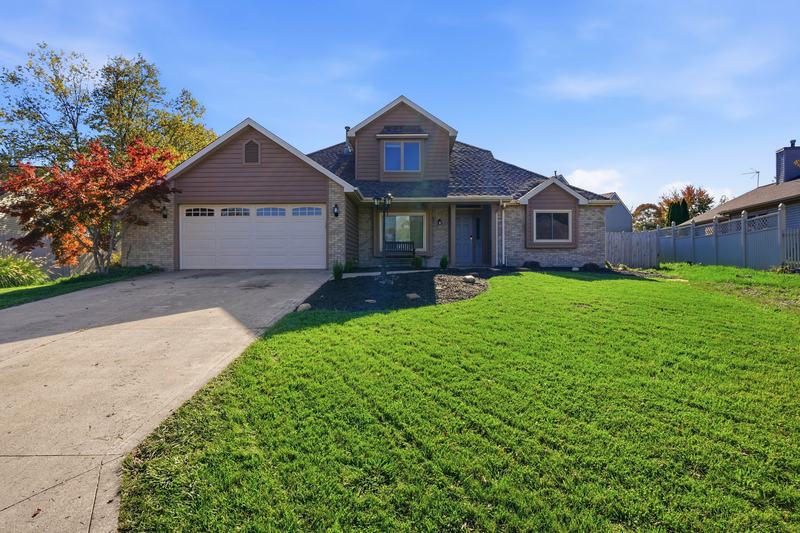 Two-story brick and siding home with a manicured lawn and fall color